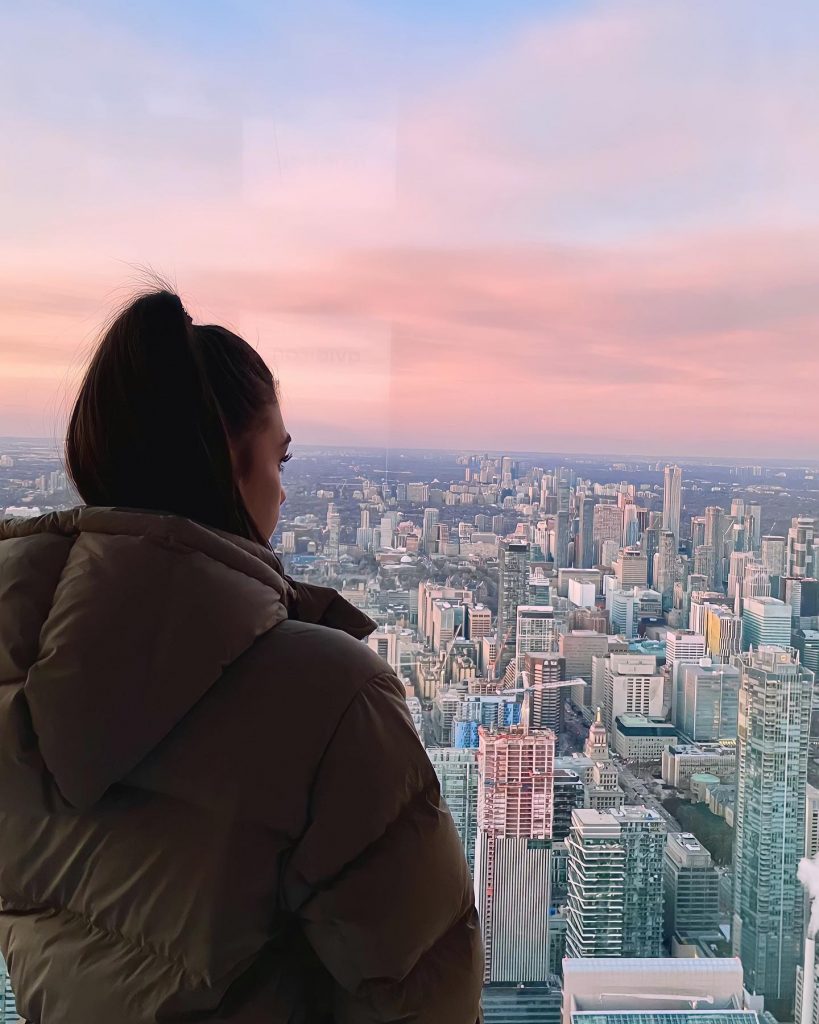 fille de dos qui regarde la vue de Toronto avec un coucher de soleil rose